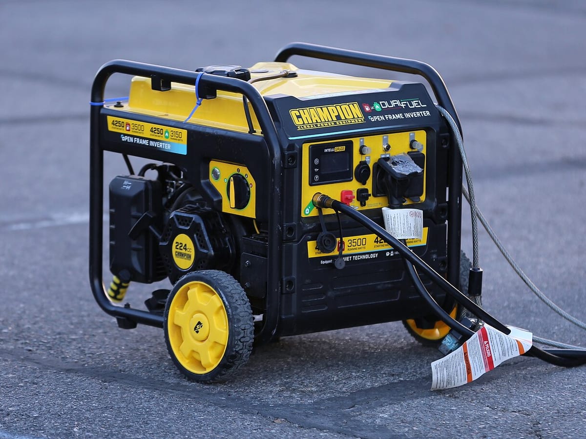 A dual-fuel inverter generator running outdoors with a cord plugged in